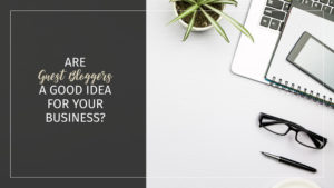 Text: Are Guest Bloggers a Good Idea for Your Business? Background: White desktop with glasses, a plant, a pen and notebooks